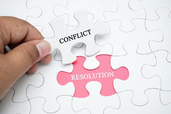 Photo illustration of man putting puzzle together, symolizing conflict resolution.