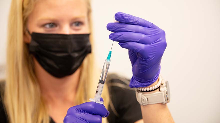 An employee of the Auraria Health Center preps a vaccine.