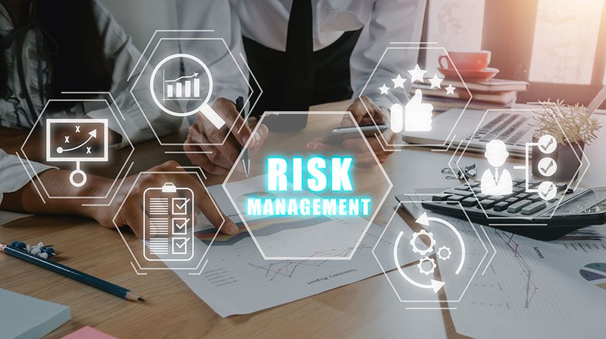 Close-up of two professionals working on documents and graphs at a desk, overlaid with hexagonal icons and the words "Risk Management" glowing in blue, symbolizing strategies and processes.