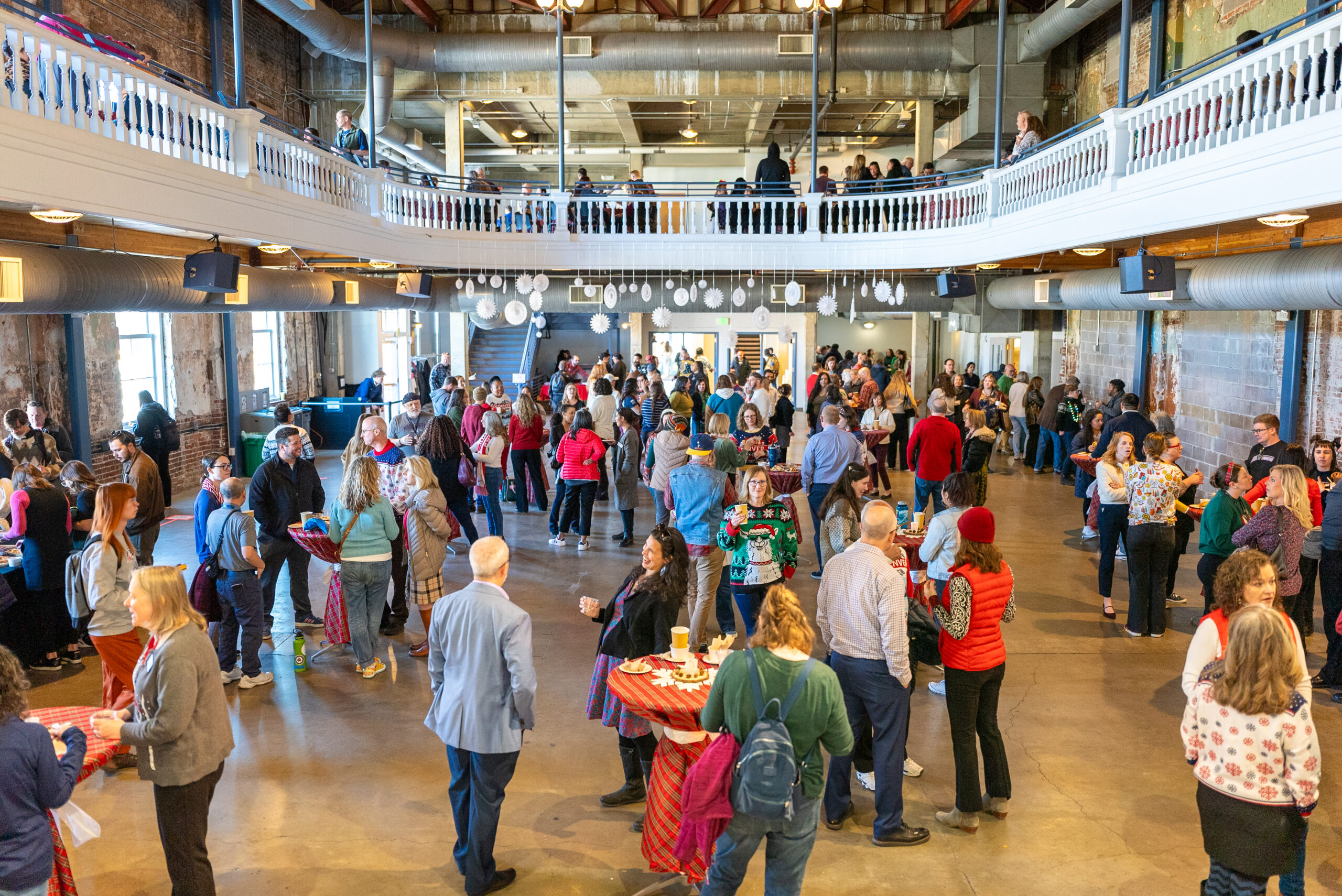 A large event space filled with people mingling during a festive holiday celebration.