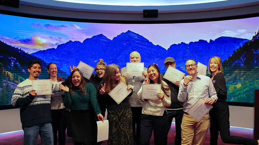 LEAD graduates at MSU Denver pose with their certificates in front of a backdrop of the mountains