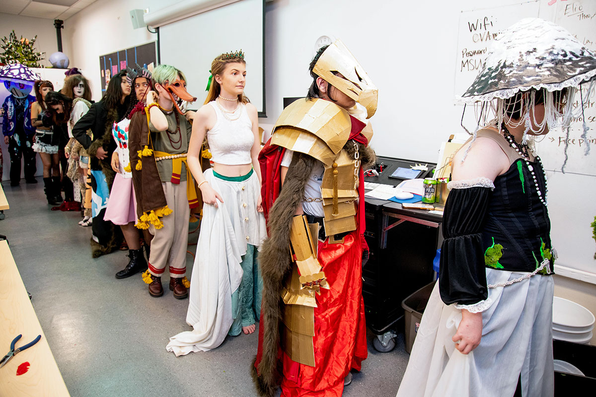 Models in fantasy and avant-garde costumes line up backstage at the Art + Action fashion show.