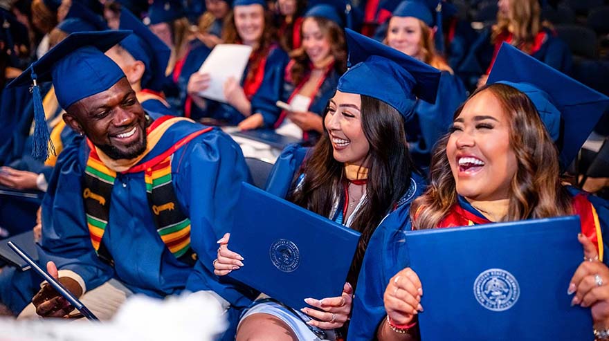 Smiling graduates with diplomas