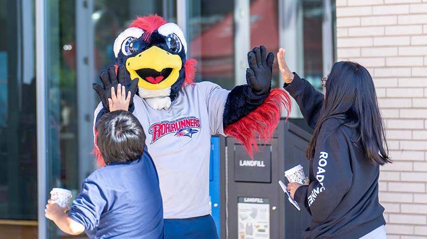 Rowdy giving a high five to two people with backs turned