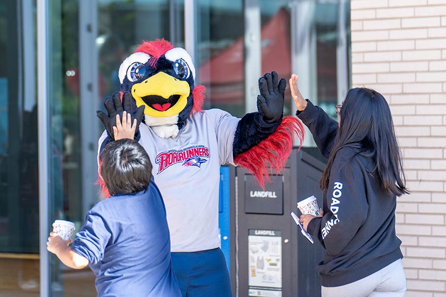 MSU Denver mascot Rowdy give high fives to students.