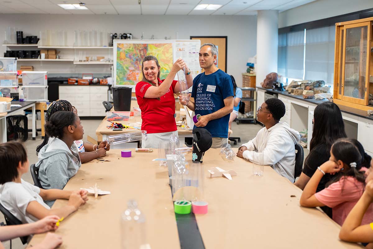 Brooke Evans, Ph.D., from the College of Aerospace, Computing, Engineering, and Design, and mathematics professor Henricus Bouwmeester, Ph.D., guide students in constructing their water rockets.