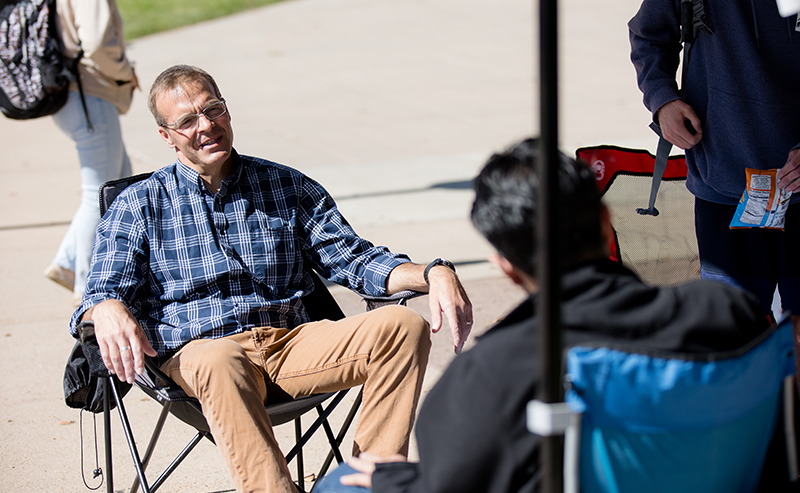 Professor Robert Preuhs speaks with a student outdoors on the Auraria Campus.