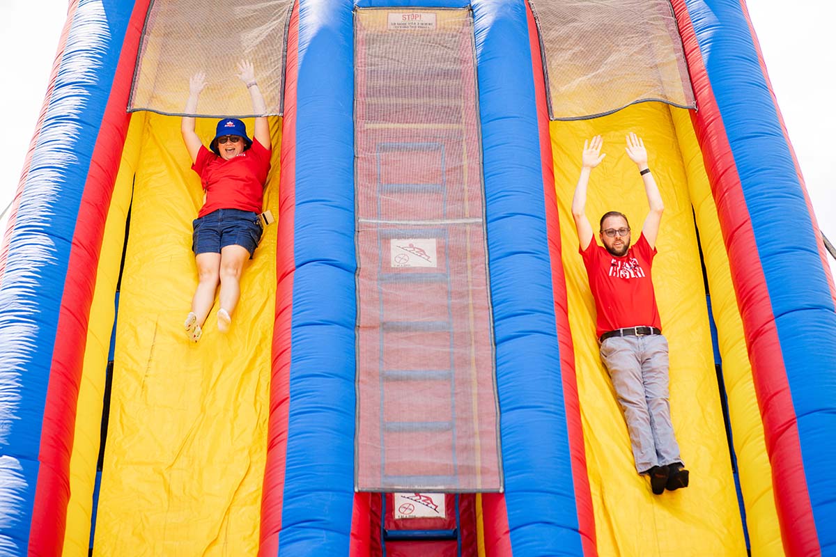 Staff go down a slide at convocation