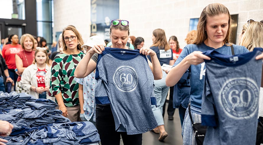 Employees pick up free t-shirts with a logo on the front that reads "MSU Denver 60 years of excellence"