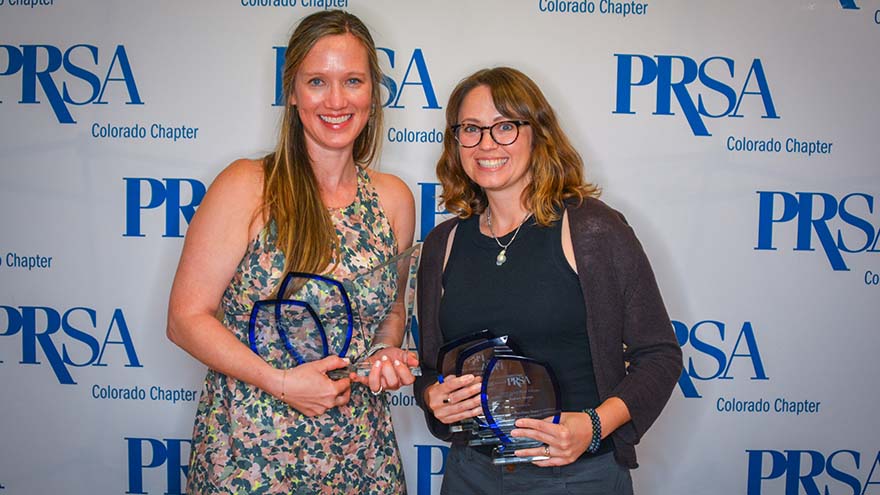 MSU Denver staff members Amanda Schwengel and Laura Miller hol awards against a PRSA Colorado backdrop
