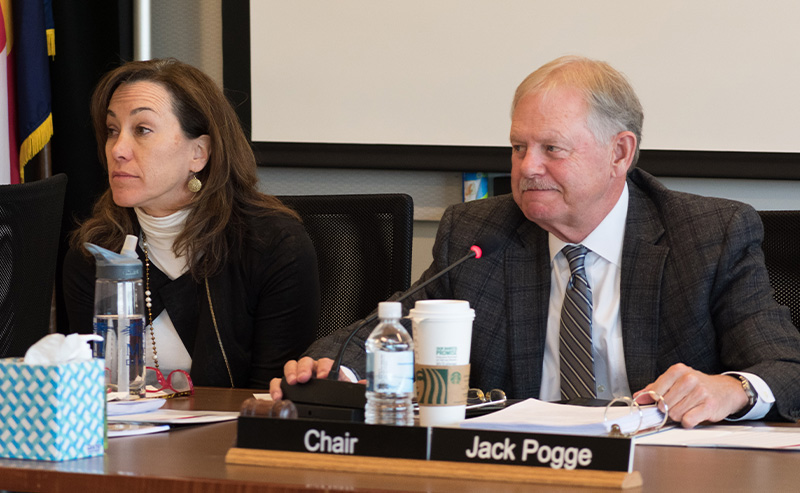 Former MSU Denver trustee Jack Pogge sits at a conference table beside another official during a board meeting. A nameplate reading ‘Chair Jack Pogge’ is in front of him.