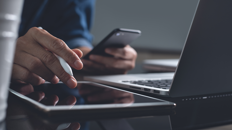Close-up of a person using a smartphone and laptop