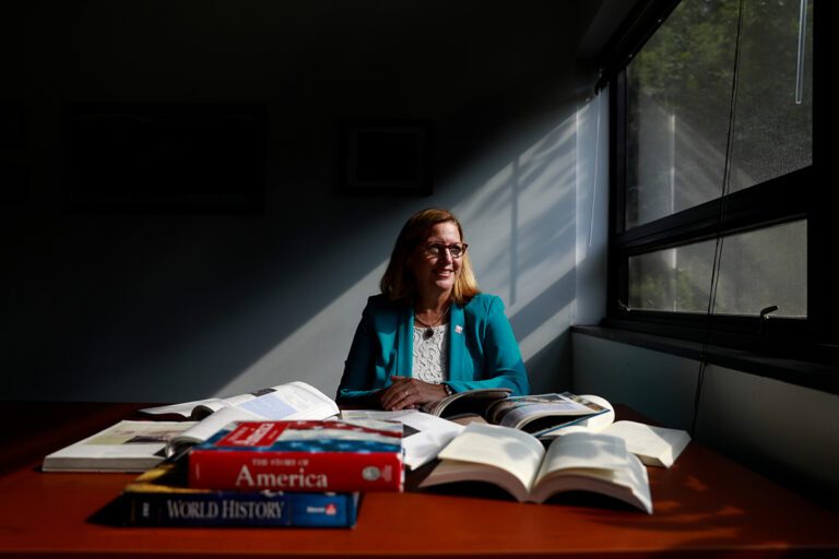 Dean Elizabeth Hinde sits at a desk with history books stacked before her.