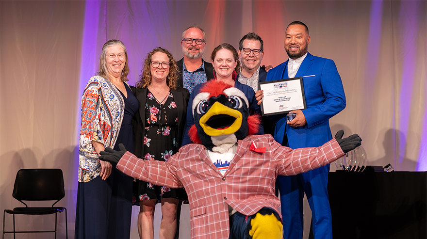 MSU Denver staff and faculty pose on stage with mascot Rowdy after receiving an award during the Roadrunners Who Soar ceremony