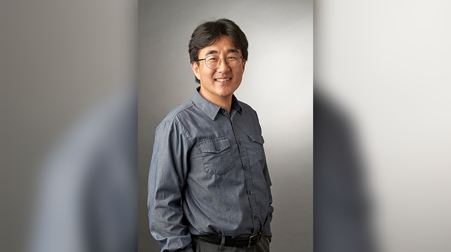 A portrait of Ted Shin, in front of a grey backdrop.