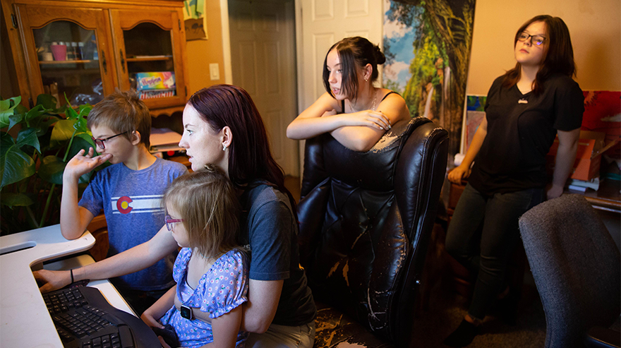 A family gathered around a computer in a home environment.