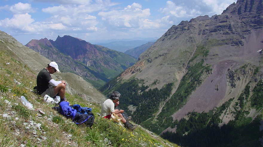 Scenic mountain landscape with two people resting on a hillside