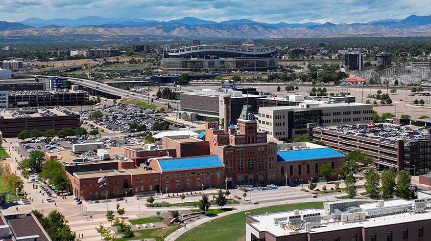 Aerial view of campus buildings and surrounding streets with mountains visible in the background.