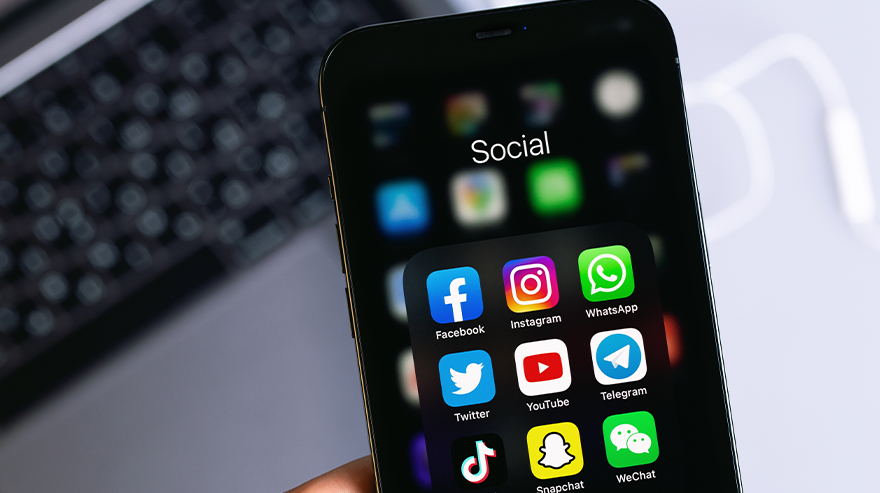 Smartphone displaying a folder of social media apps including Facebook, Instagram, Twitter, TikTok, and Snapchat.