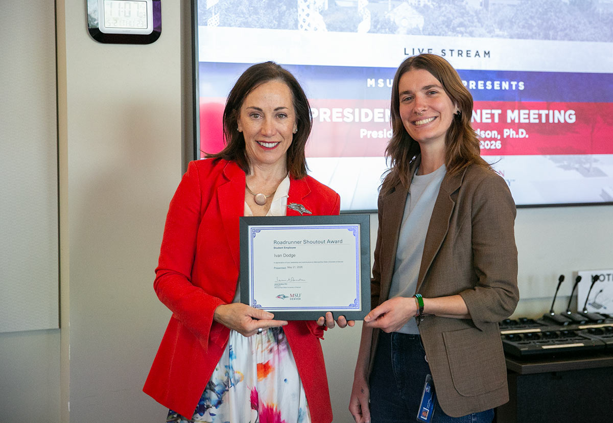 President Janine Davidson and Ivan Dodge hold a framed award honoring Dodge at the President's Cabinet meeting.