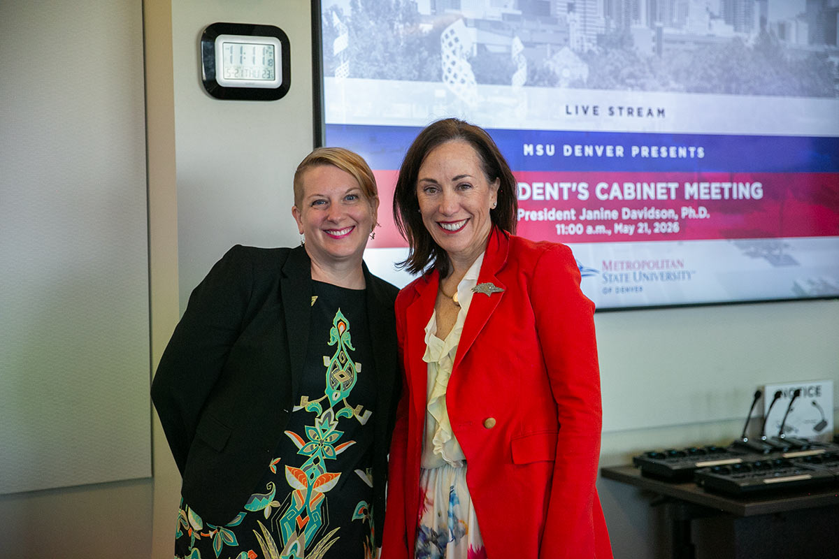 Liz Goodnick and President Janine Davidson stand in front of a screen that says "President's Cabinet Meeting"