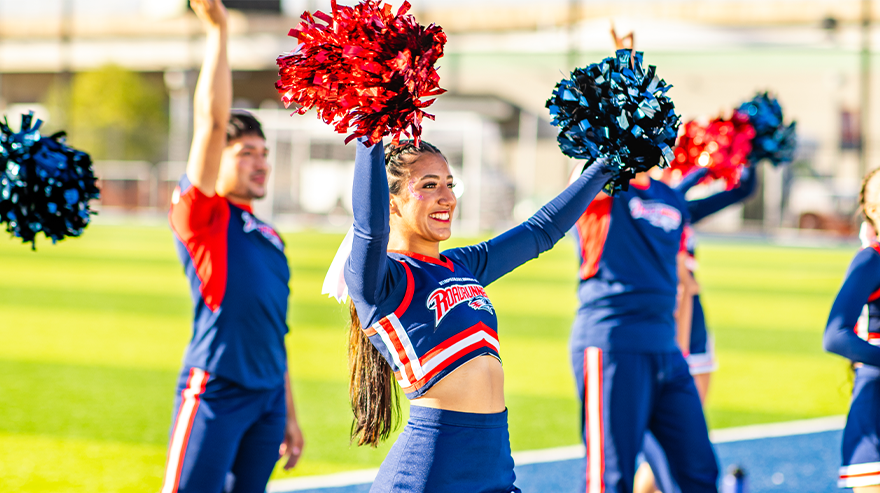 MSU Denver cheerleaders performing outdoors with red and blue pom-poms during a campus event.