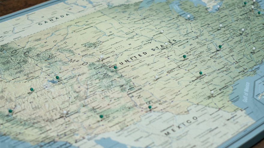 Close-up of a map of the United States with colored push pins marking locations across multiple states.