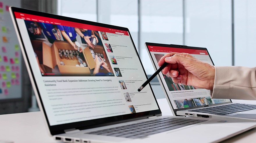 Woman's hand appears in front of two laptops displaying online news articles