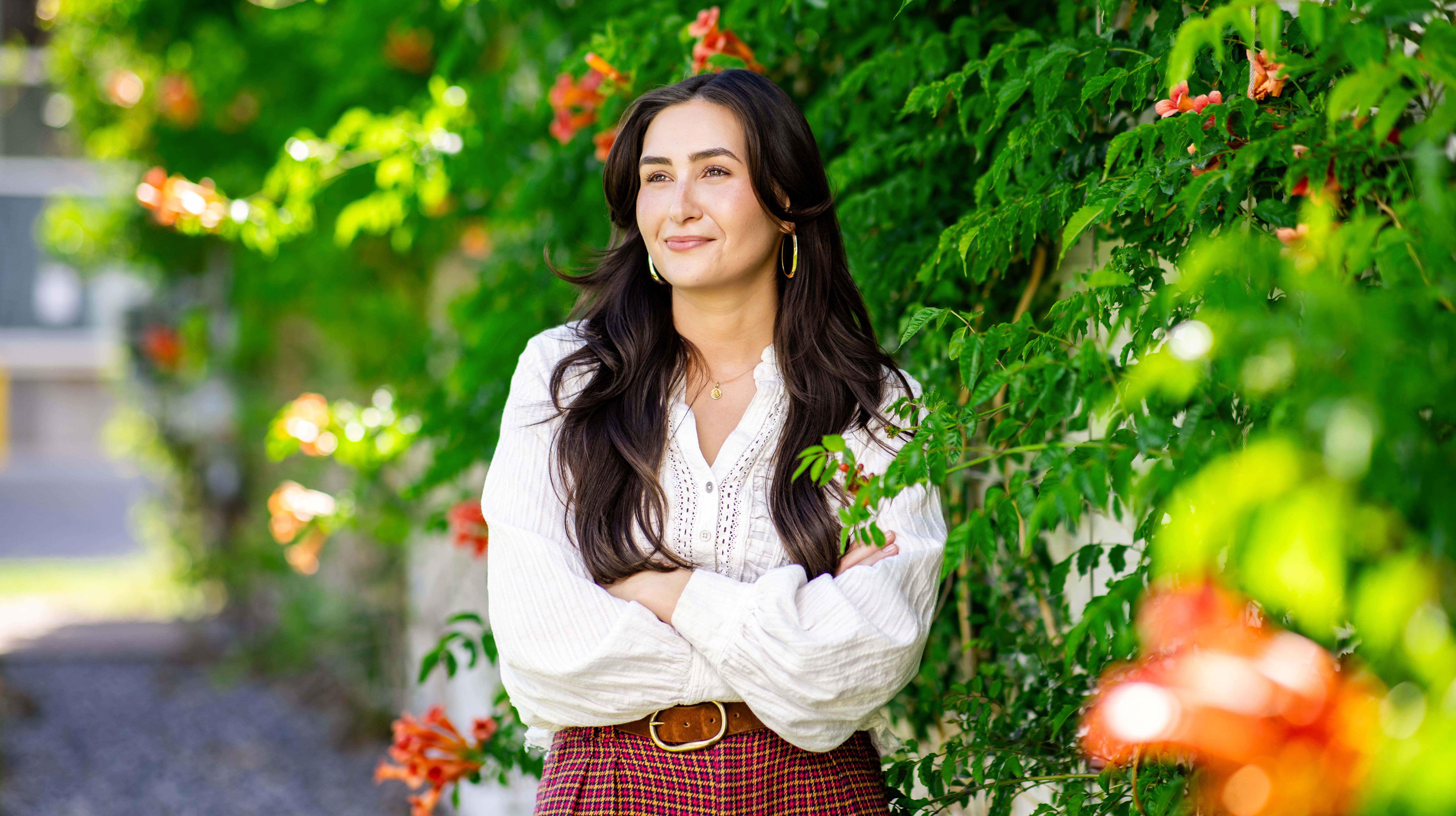 Margarita Driscoll stands in front of green bush branches