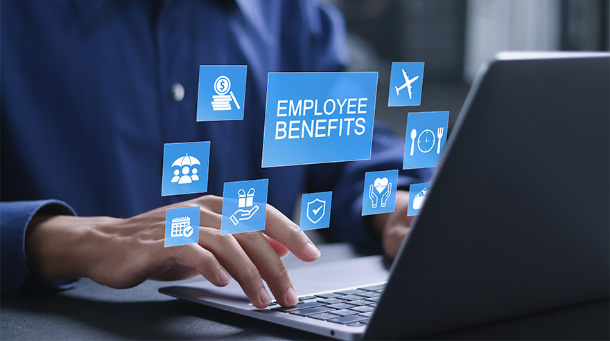 A employee sitting at a desk using a laptop with a graphic over the top saying "Employee Benifits".