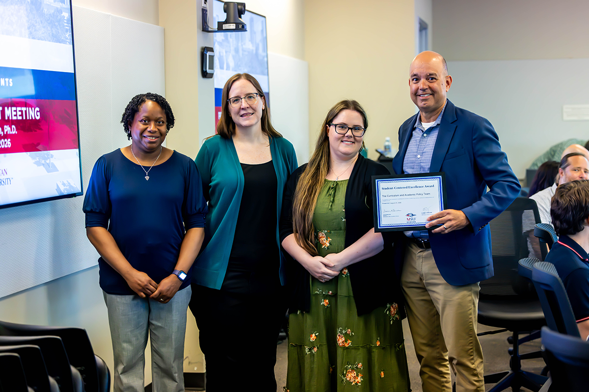 Jim Carpenter, interim president and CFO, presents a Student-Centered Excellence Award to Erica Buckland Anderson, director, along with Maggie Aurich and Tonia Schneider of the Curriculum and Academic Policy Team