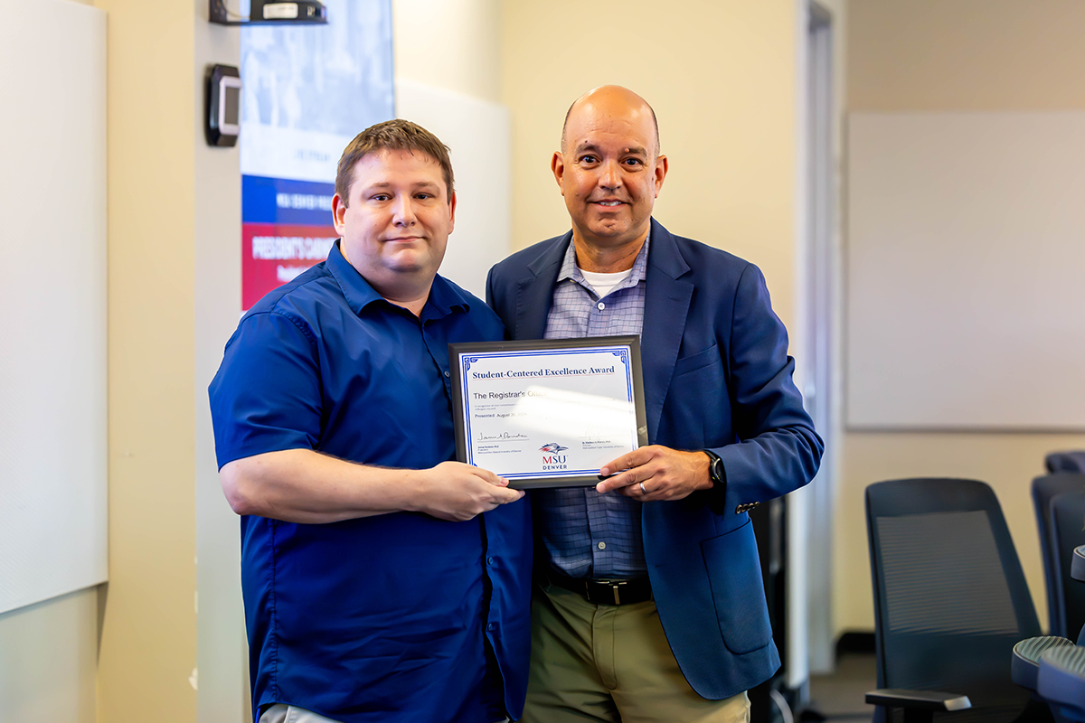 Jim Carpenter, interim president and CFO, presents a Student-Centered Excellence Award to Jesse Ehringer, associate registrar, and the Registrar's Office.