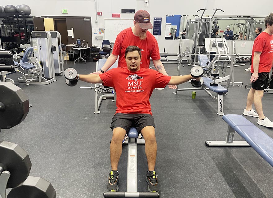 Exercise science student trainers demonstrate an exercise in the gym.