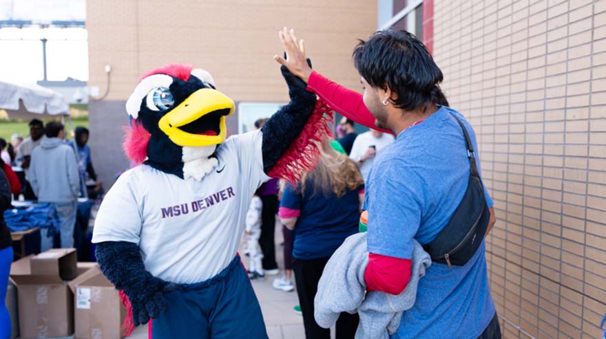 Rowdy gives high fives as Roadrunner 5k participants check in and grab shirts.