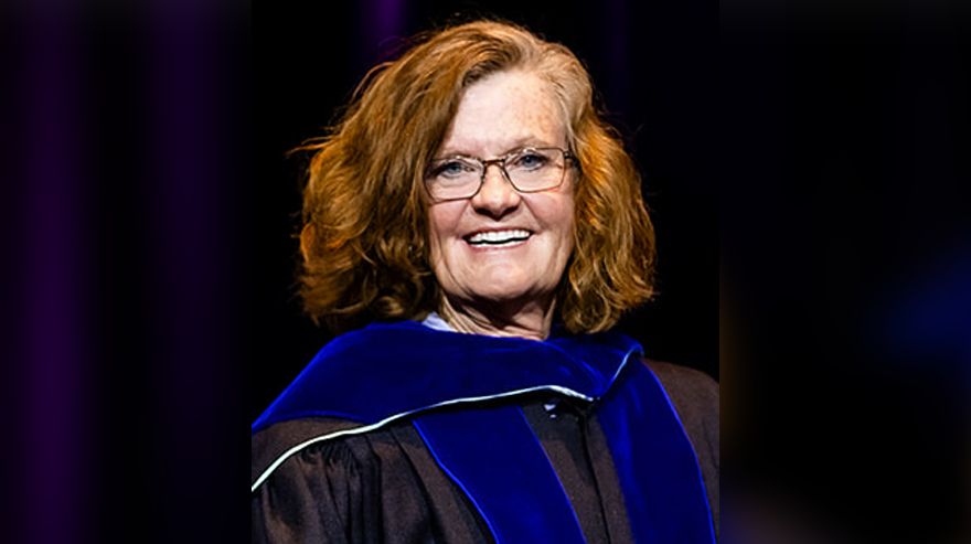 Portrait of Eileen Starr in Commencement regalia with a dark background