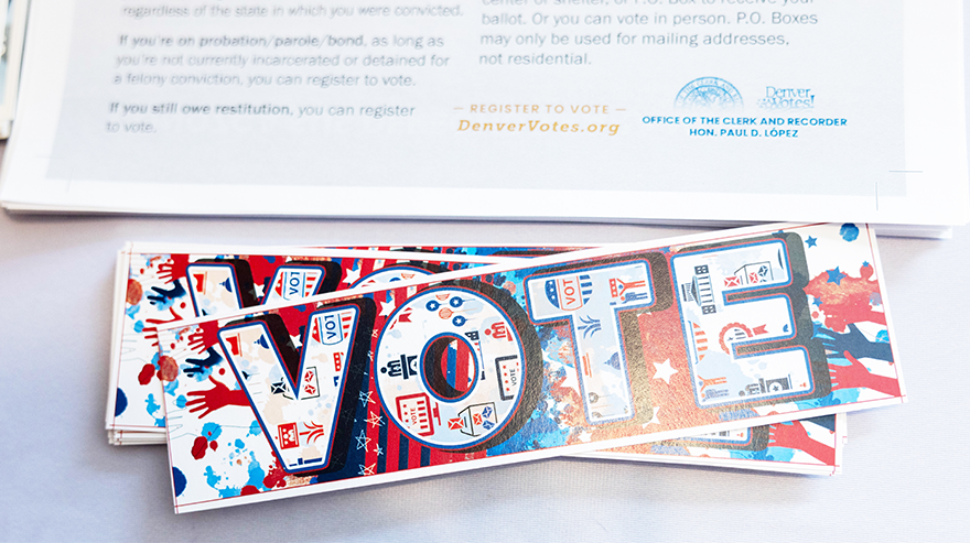 Close up of a bookmark with the word "vote" in capitals amid a combination of many graphics using MSU Denver red and blue colors