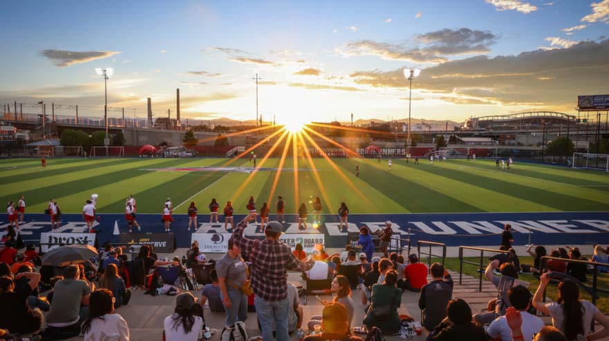 The sun sets over the women's soccer game.