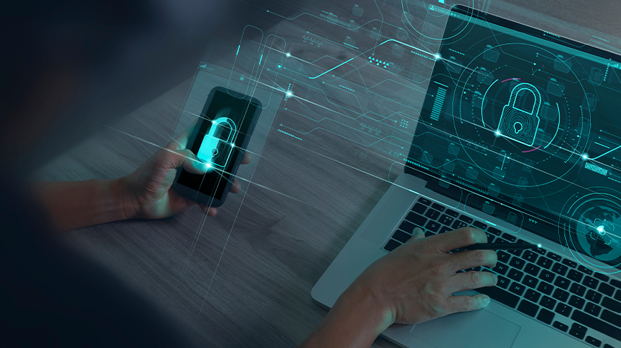 A stock image of a person's hands hovering over a laptop and holding a phone is overlain with graphics of locks and other technology-related symbols