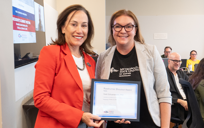 President Janine Davidson poses for a photo with Keah Shuenemann as both hold a Roadrunner Shoutout Award plaque addressed to Shuenemann